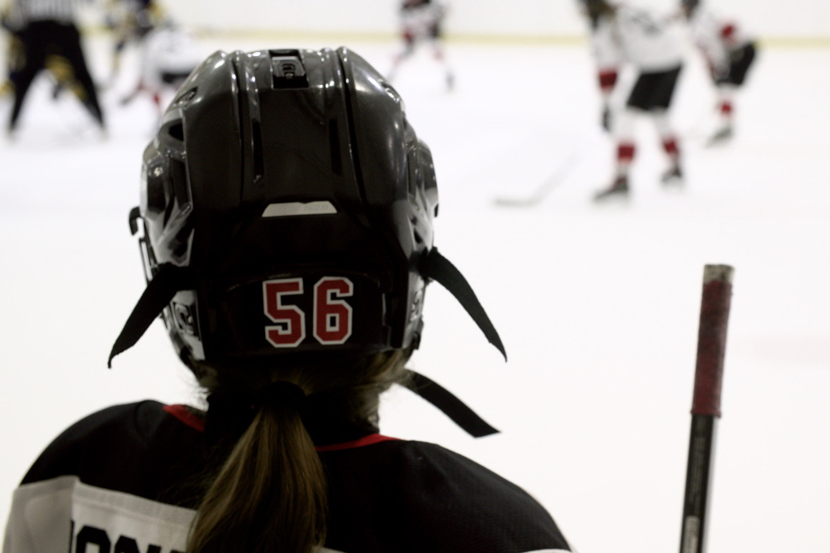 Utica Jr. Comets Girls team player Rowan Hockman watches her teammates playing ice hockey.