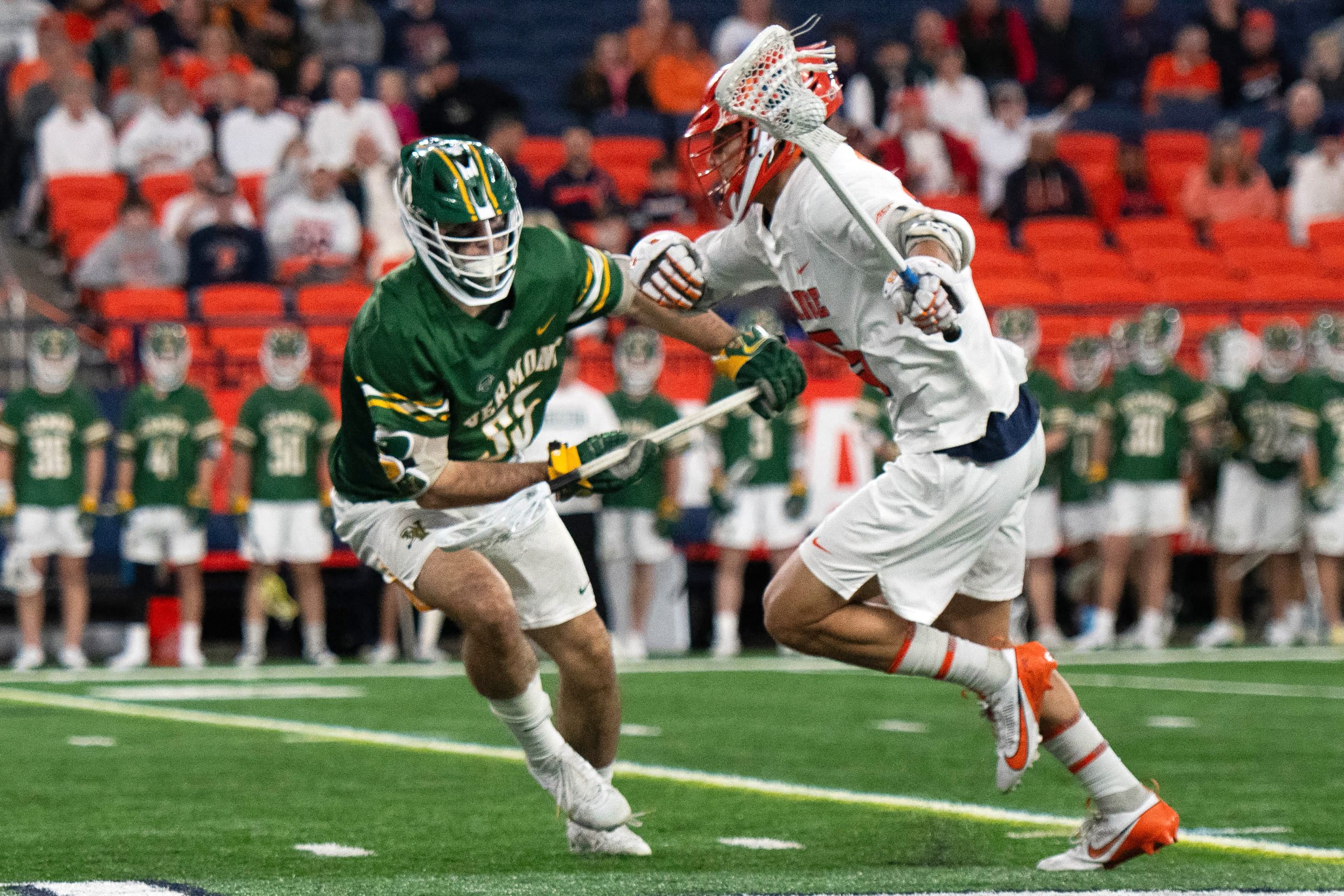 Sam English (15) wards off the short stick defensemen.