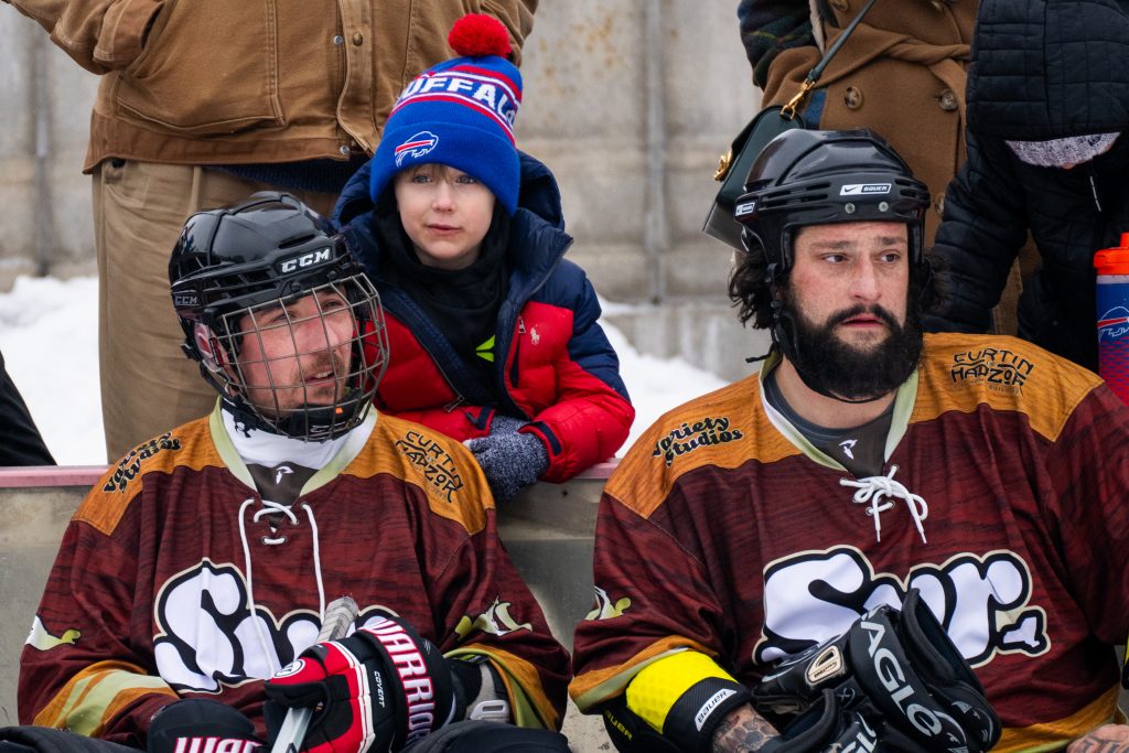 Variety Studios team members watch their game on the sidelines with family during the Syracuse Pond Hockey Classic at Clinton Square in Syracuse on Jan. 25, 2025.