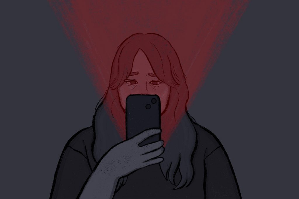 Girl looking down at her phone with a red light shinning through.