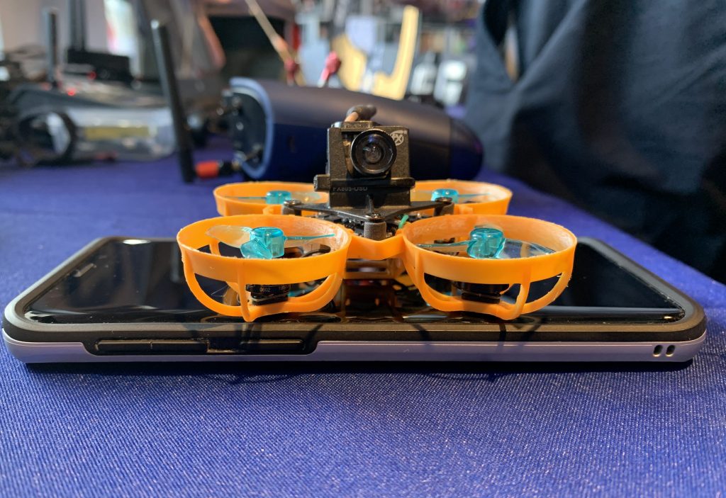A tiny drone sits on a smartphone.