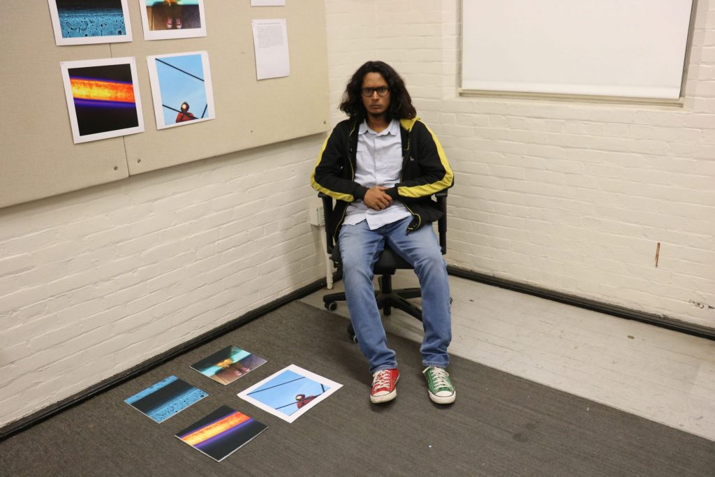 Anshul Roy poses in front of his photography work in his studio at Smith Hall.