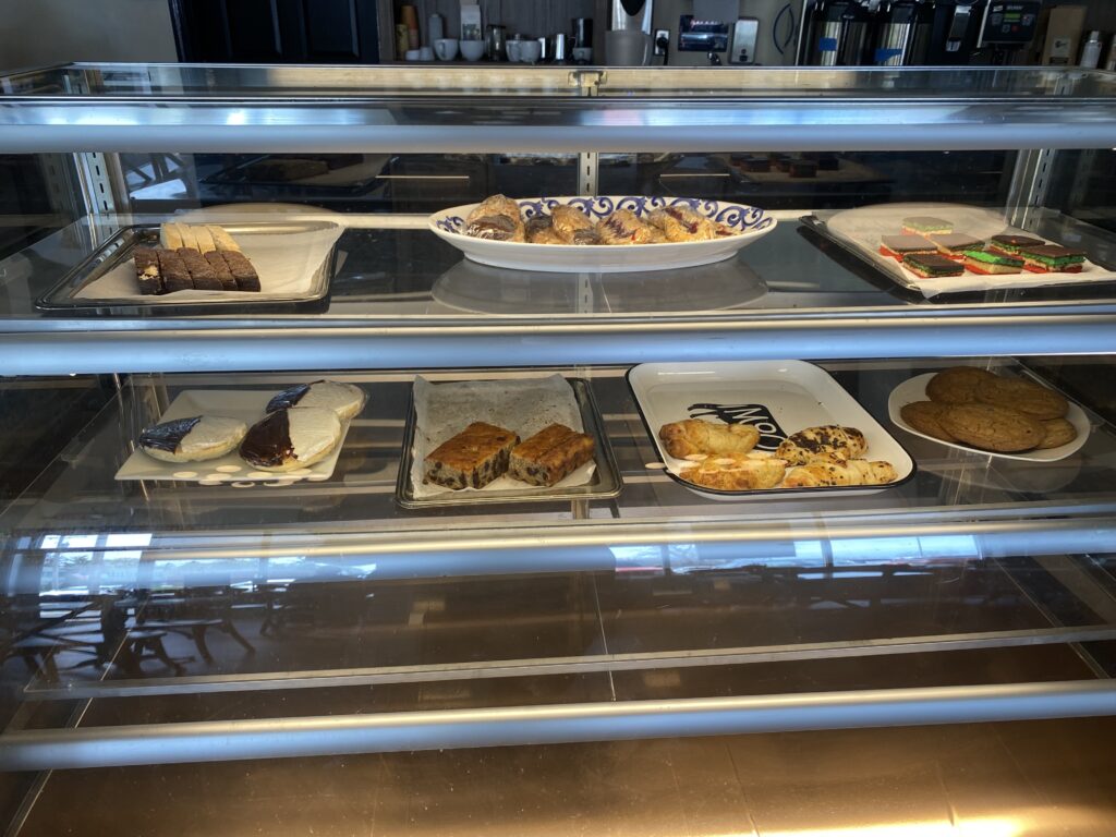 A coffee shop clear case that has trays of pastries including different breads, cookies and croissants.