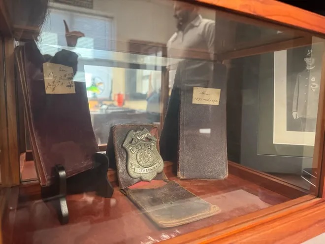 Ronald Eveland, seen through display case, is a fourth-generation police officer and has been Geneva’s police chief since June 2024. He said he is confident in his officers’ ability to perform their duties.