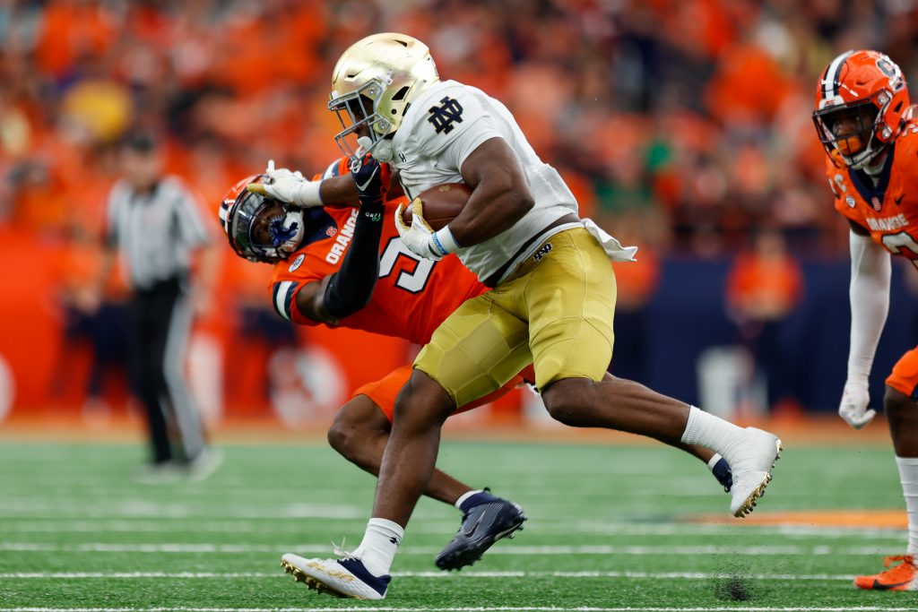 SYRACUSE, NY - OCTOBER 29: Audric Estime #7 of the Notre Dame Fighting Irish stiff arms Alijah Clark #5 of the Syracuse Orange at JMA Wireless Dome on October 29, 2022 in Syracuse, New York. (Photo by Isaiah Vazquez/The Newshouse)