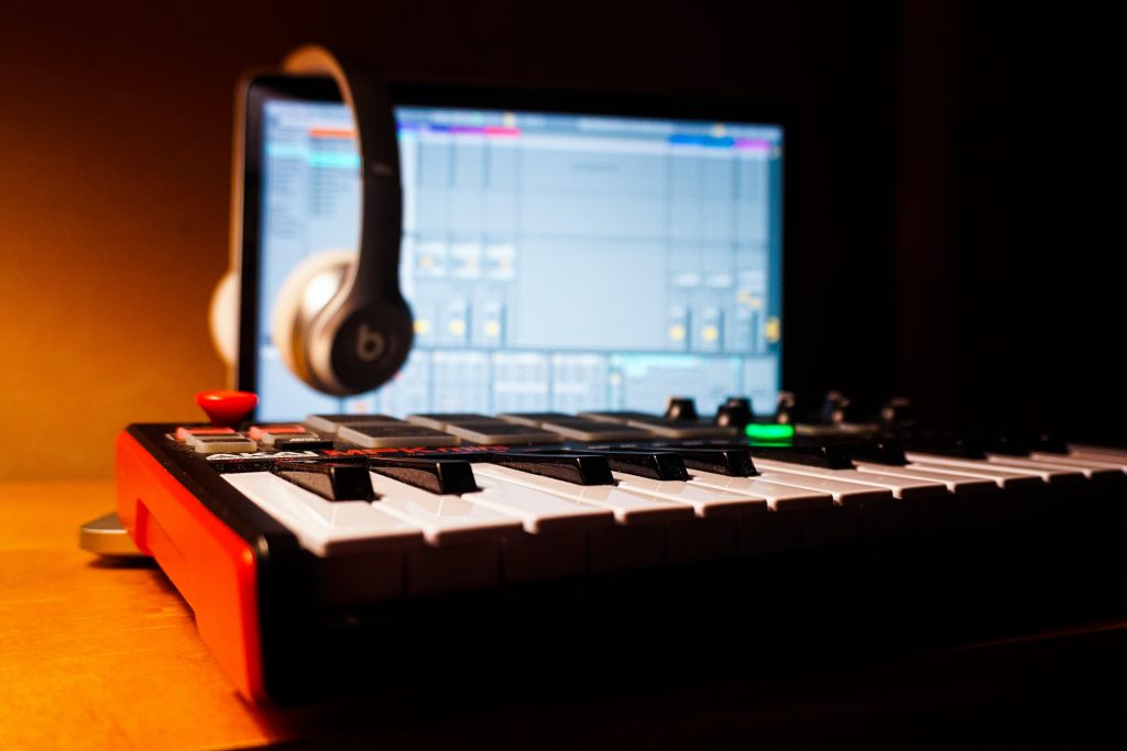 A pair of headphones hangs over a laptop behind a keyboard.