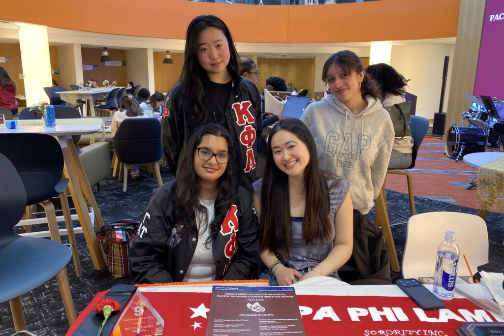 Four female students post for a photo representing their cultural sorority that is participating in tabling for the kickoff.