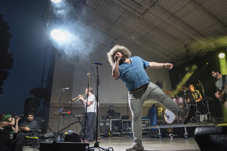 Ripe frontman Robbie Wulfsohn kicks a leg into the air while racing across the Paper Mill Island stage Friday night. His animated performance matched the band’s funk-heavy sound, keeping the crowd moving throughout the headlining set. Photo by Matt Hofmann.