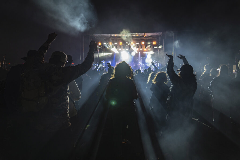 Fans raise their hands through a haze of smoke during Slightly Stoopid’s performance at Beak & Skiff Apple Orchards. Cannabis has long been woven into the band’s music and culture, extending from songs such as “Collie Man” to the group’s own Stoopid Organics brand. Photo by Matt Hofmann.