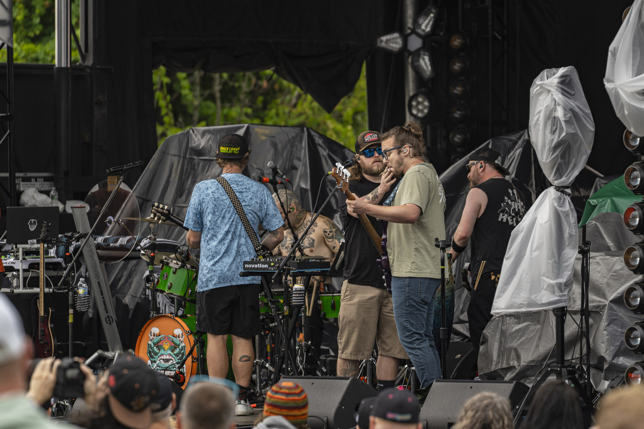 A Bumpin Uglies crew member passes a joint to bassist Brent Schraffenberger during the band’s opening set at Beak & Skiff Apple Orchards. Throughout the performance, the crew member moved around the stage lighting up and sharing with band members, and at one point stepped to the microphone to sing “Boats and Hoes.” Photo by Matt Hofmann.