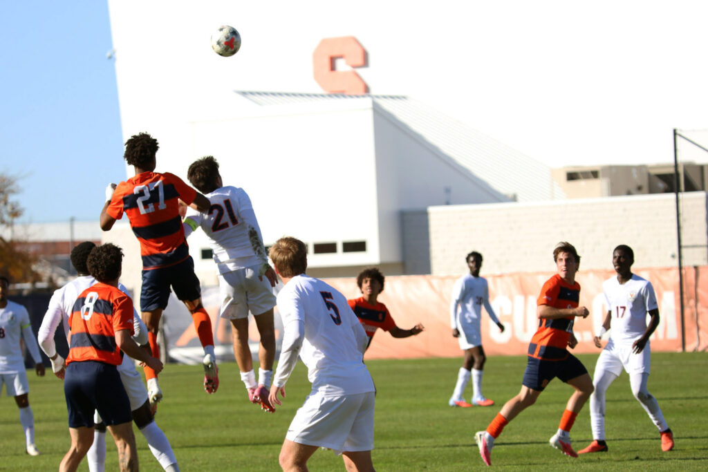 Syracuse defender Garrett Holman jumps over Virginia midfielder Kyndal Shuler to advance the ball to his teammate during the Syracuse-Virginia men's soccer game on October 24, 2026, at SU Soccer Stadium.