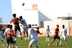 Syracuse defender Garrett Holman jumps over Virginia midfielder Kyndal Shuler to advance the ball to his teammate during the Syracuse-Virginia men's soccer game on October 24, 2026, at SU Soccer Stadium.