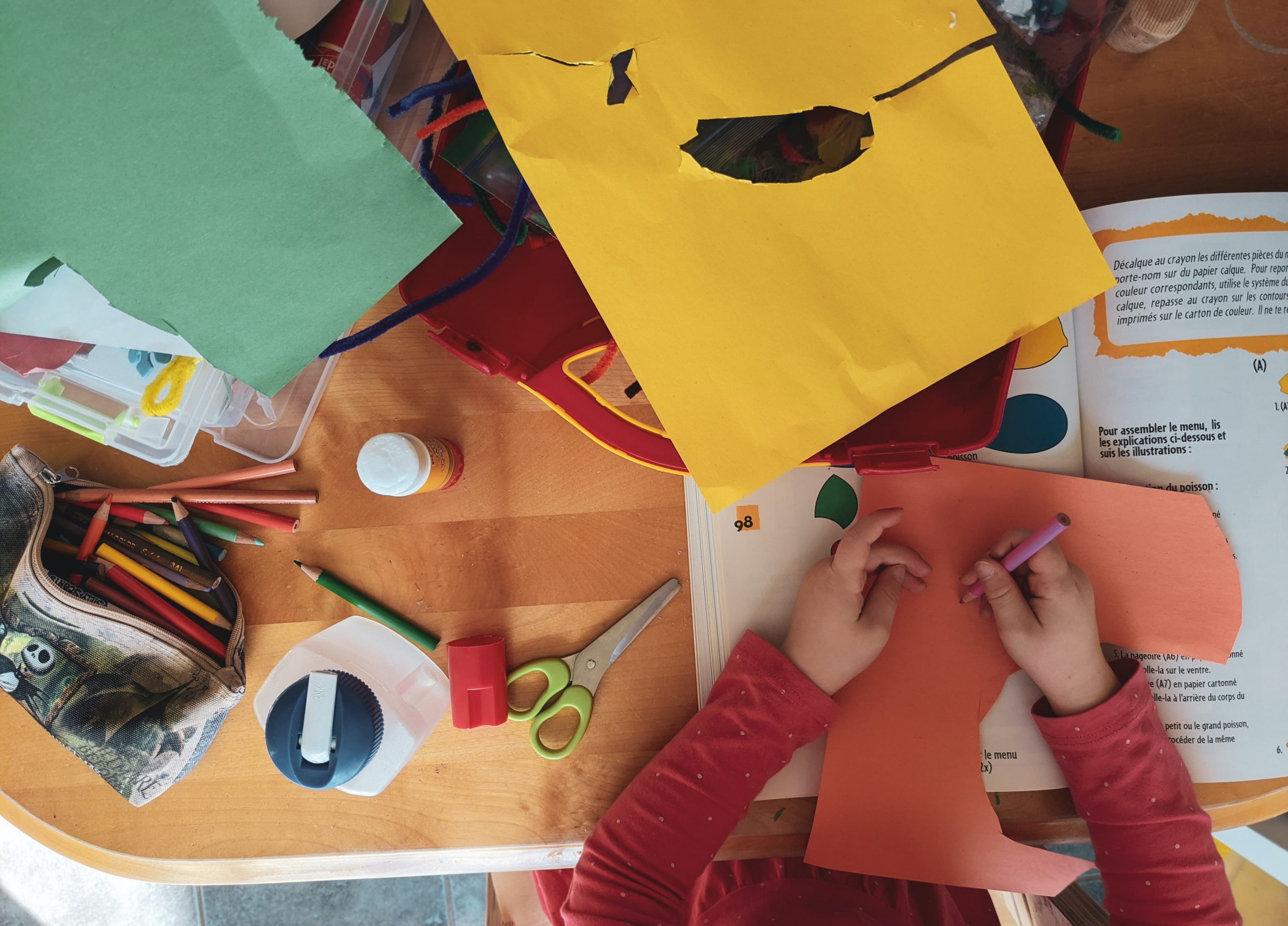 A person does an arts and crafts project with various supplies.