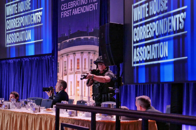 Getty Images photographer Andrew Harnik takes photos as agent points his weapon after an incident at the annual White House Correspondents Association Dinner April 25, 2026 in Washington, DC. According to reports, President Donald Trump, along with other government officials, were evacuated from the Washington Hilton after what sounded like gunfire.