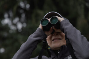 Katy Weil, a senior natural resource scientist and wildlife biologist at Metro Portland, scans a park withi binoculars in the Portland, Oregon area.
